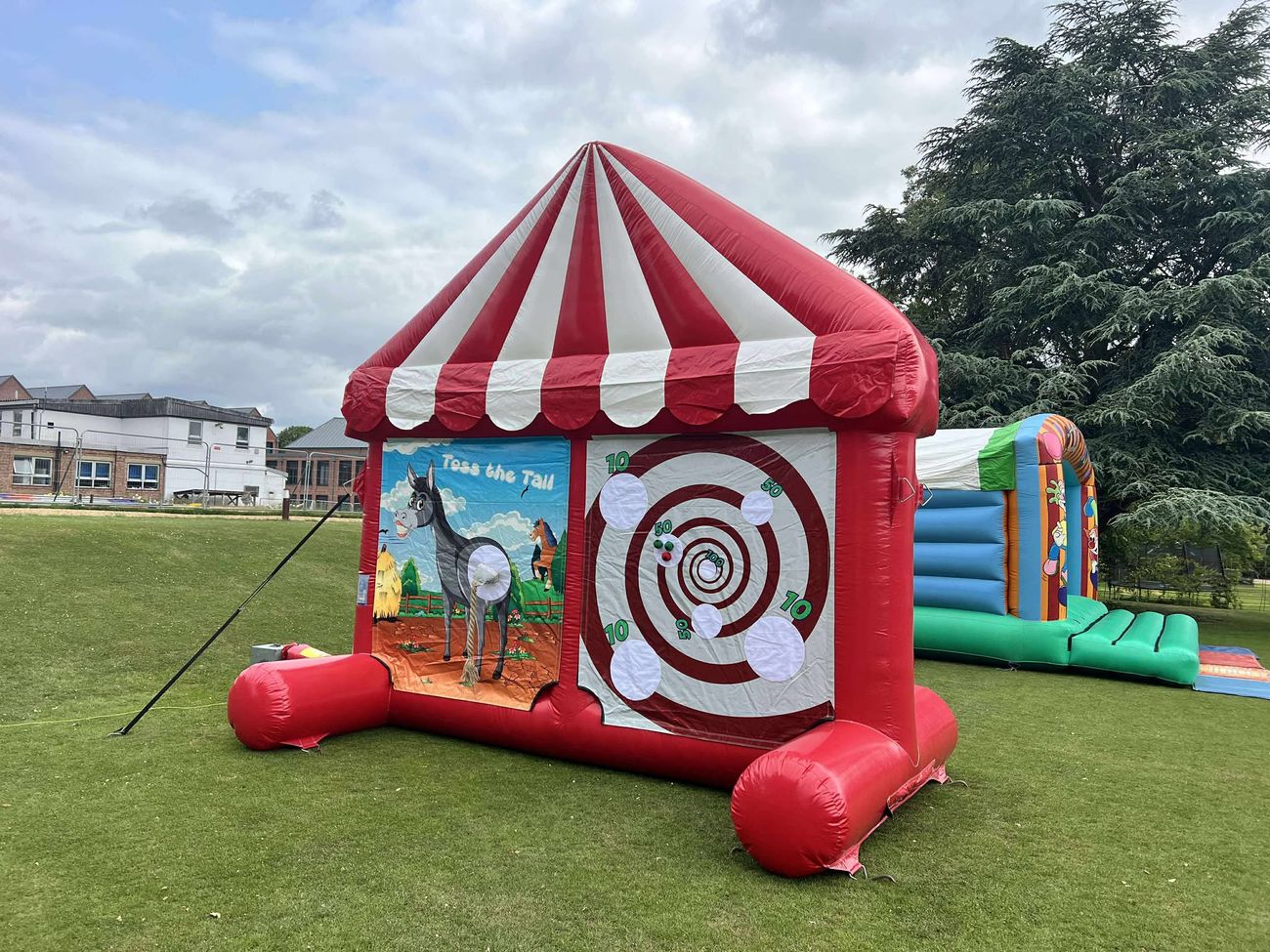 4 in 1 Carnival Game inflatable with a red and white big-top canopy set up on grass
