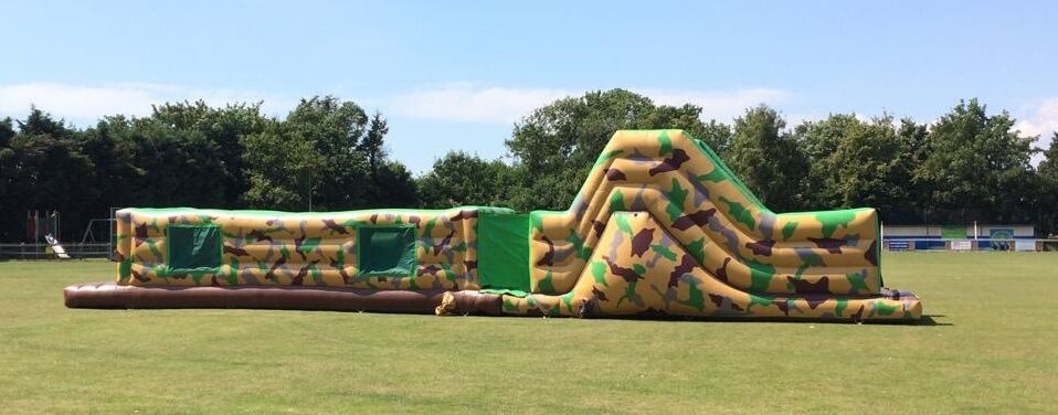 Field setup of the 50ft army inflatable assault course with trees in the background