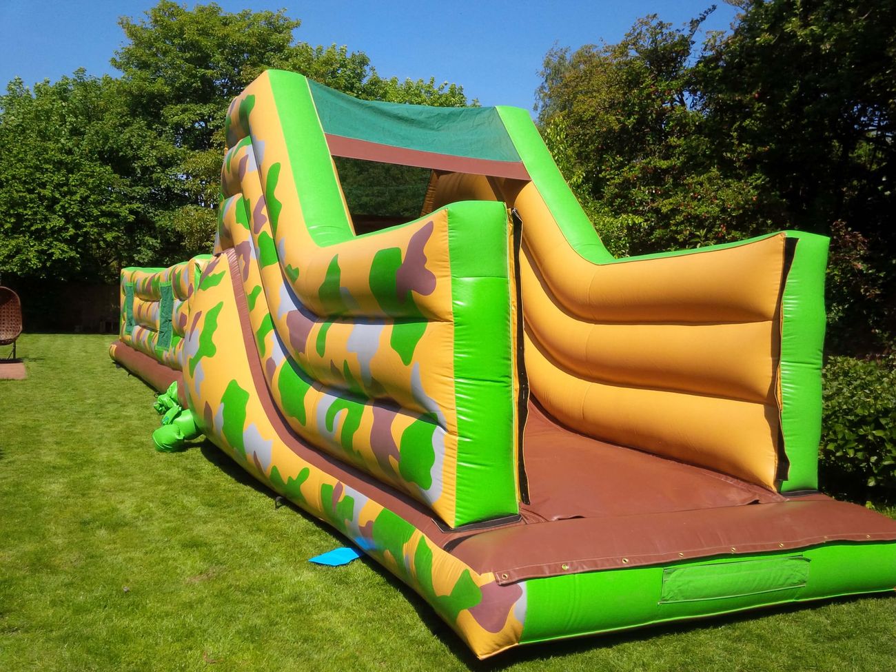 Army assault course set up on a garden lawn with camouflage walls and slide