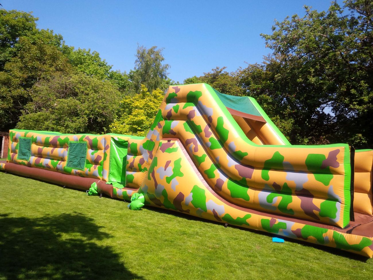 Side view of the 50ft army assault course on grass, showing tunnel sections and slide