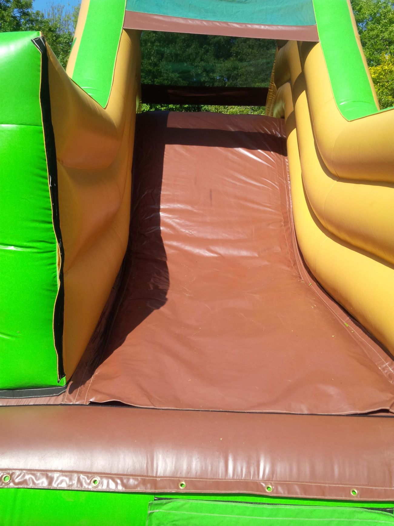 Close-up of the brown and green slide and landing area at the end of the assault course