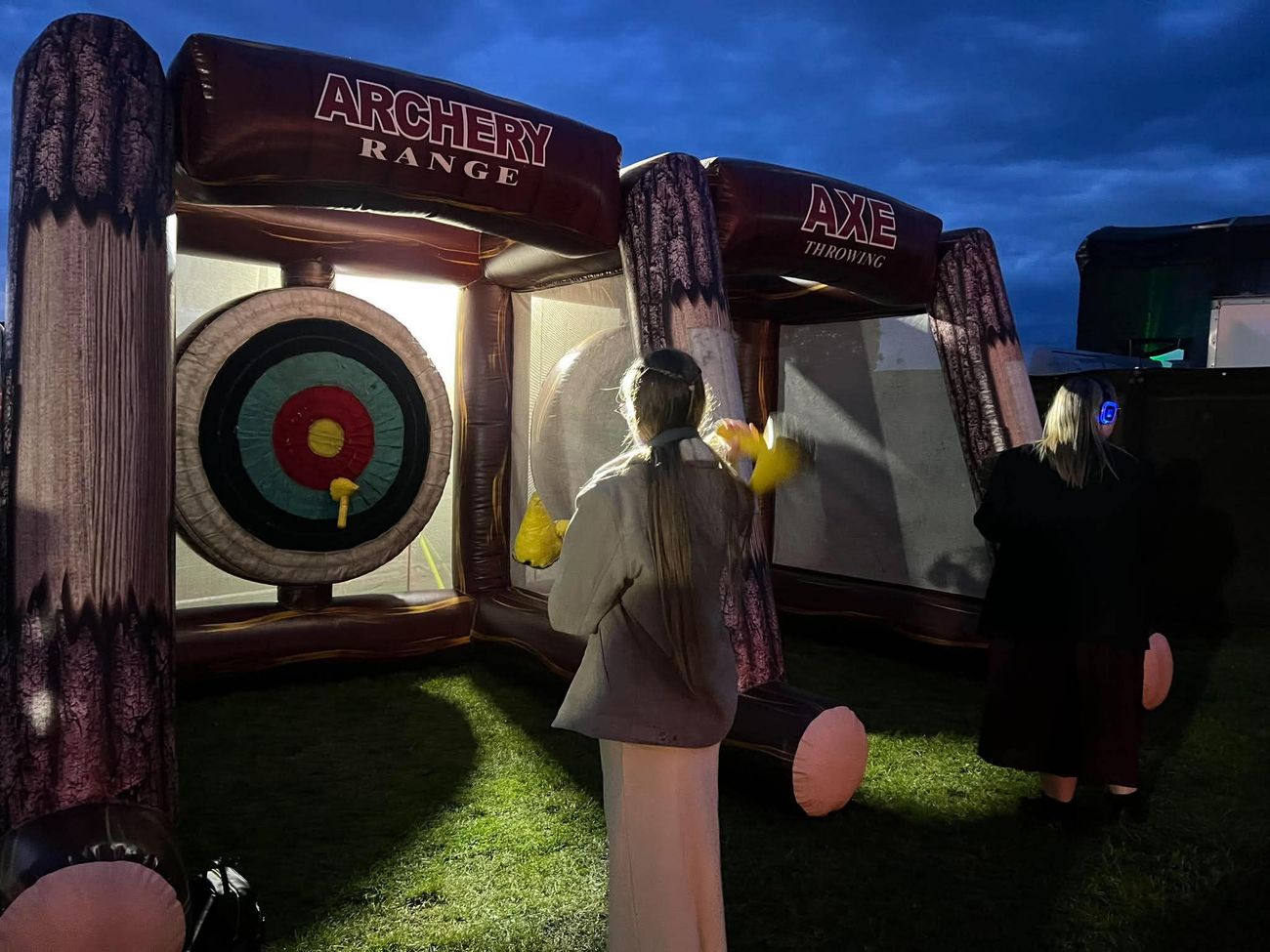 Archery and axe throwing inflatable range in use at an evening event