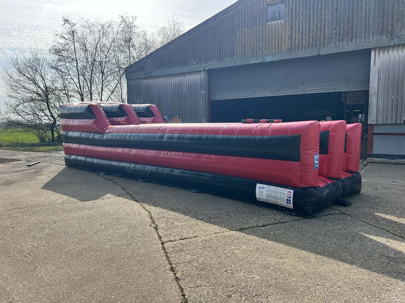 Red and black dual-lane bungee run inflatable with padded starting blocks and finish line posts