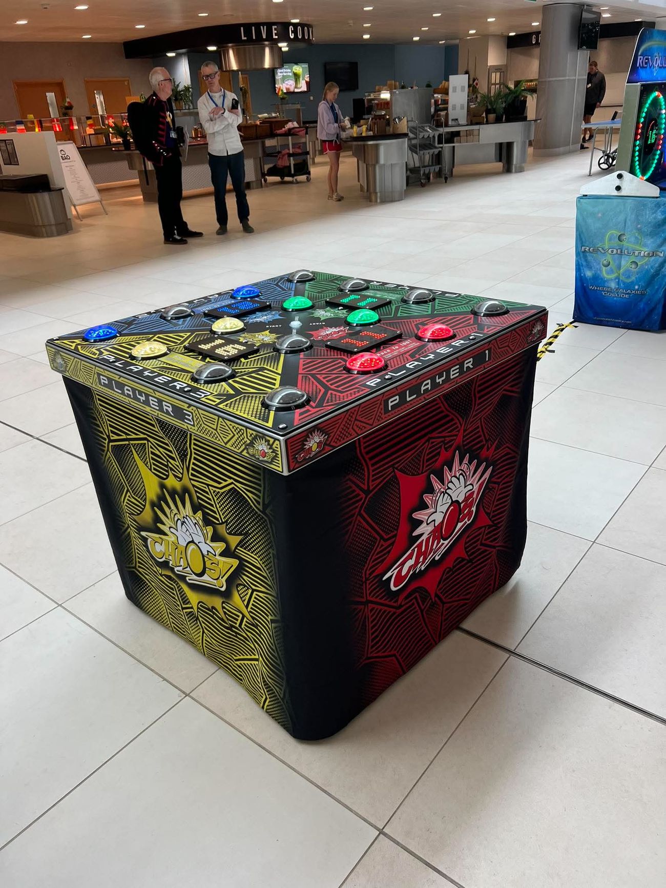 Chaos four-player reaction game cube with coloured light-up buttons at an indoor event