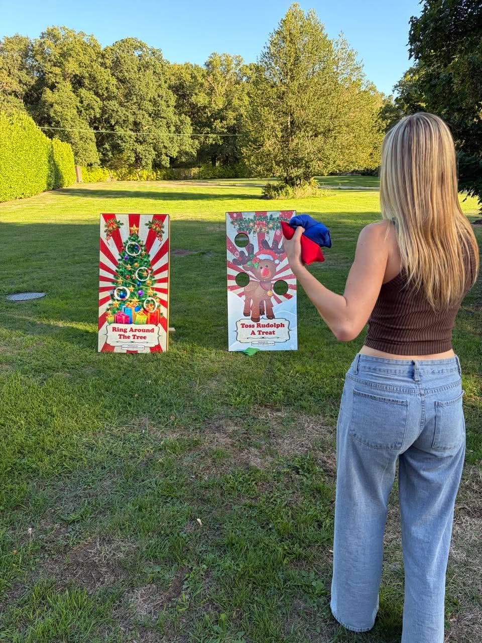 Player throwing beanbags at the Rudolph toss board with the Ring Around the Tree board beside it