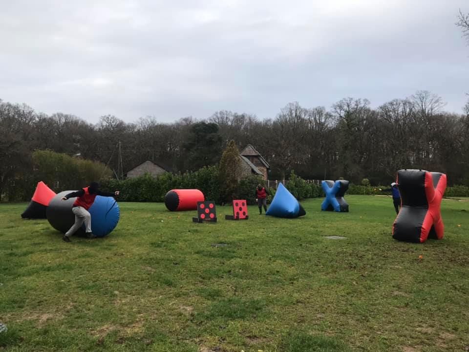 Wide view of a tag archery arena with multiple inflatable obstacles and players taking cover