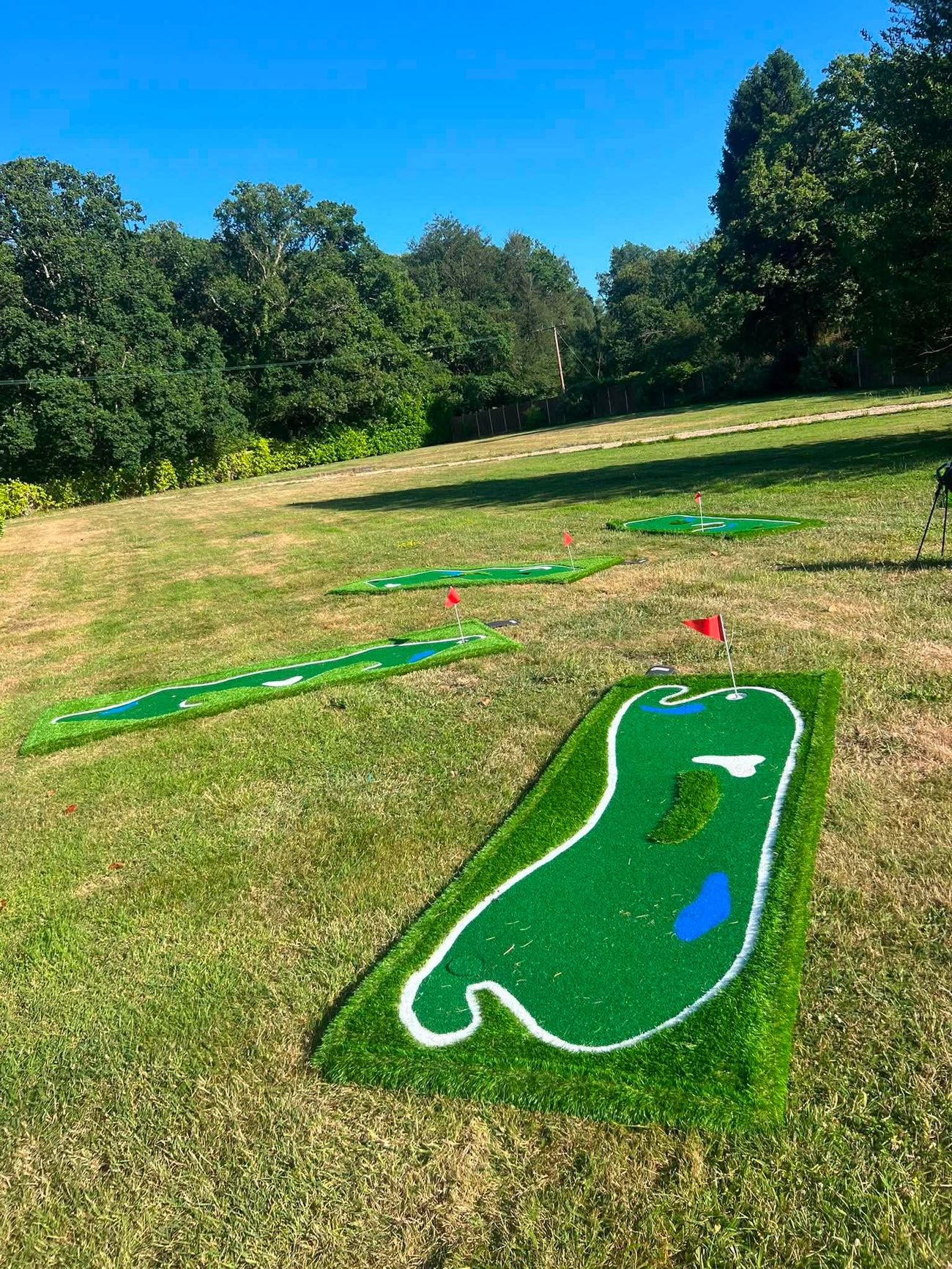 Close view of a winding mini golf hole with red flag on a summer lawn