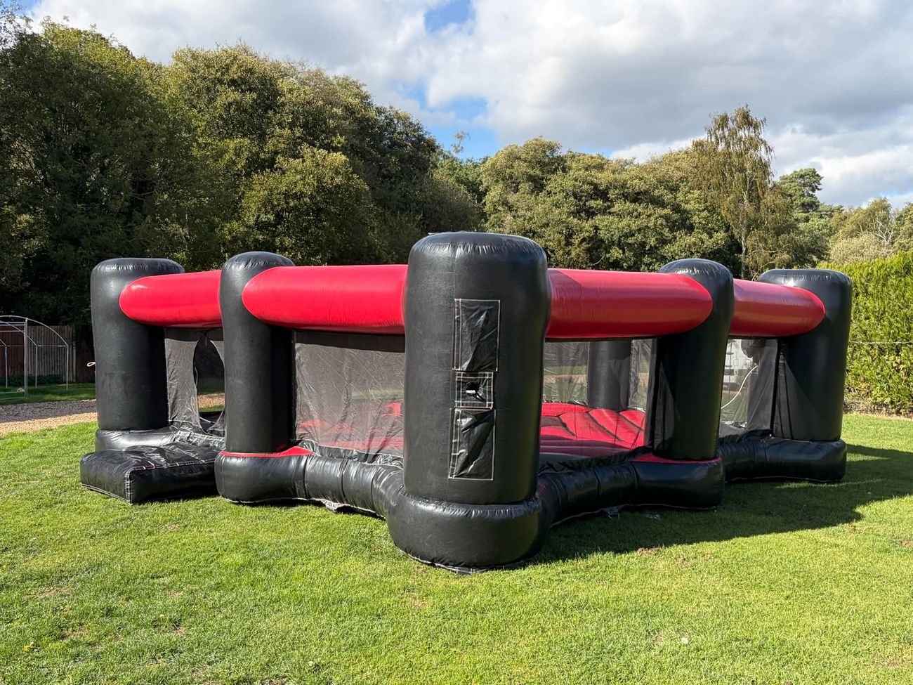 Black and red 4 player Dash N Grab arena inflated on grass, four corner pillars and mesh walls