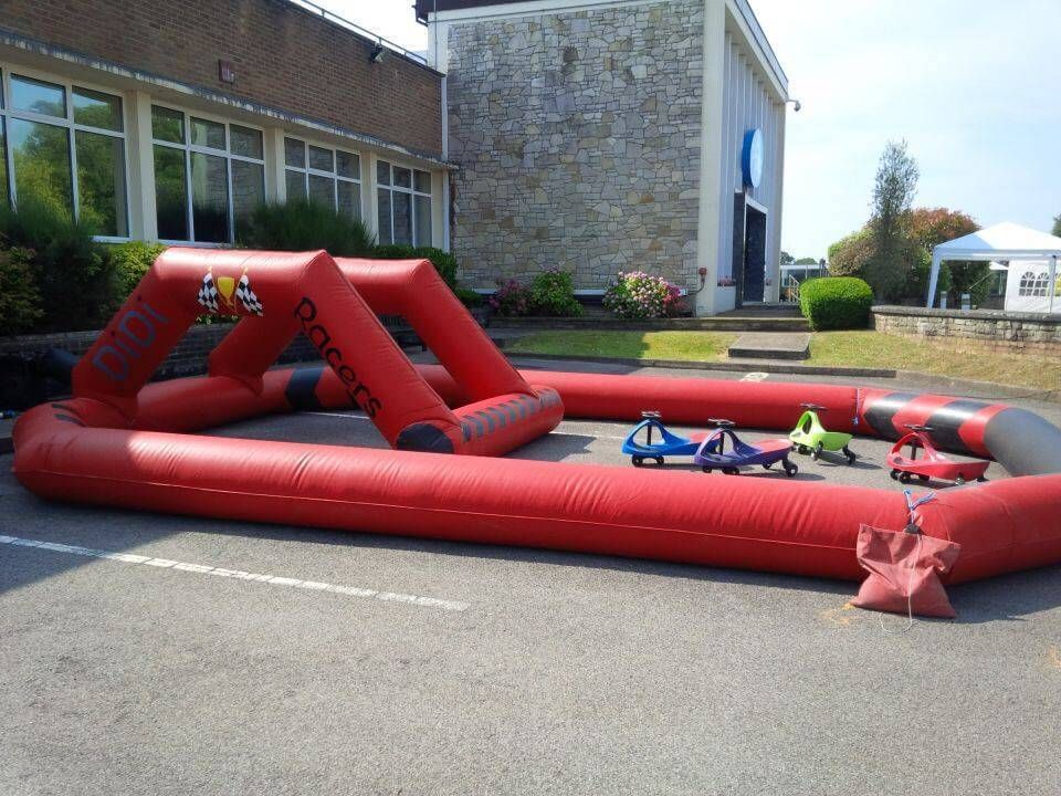 Red and black inflatable Didi Racers track with chequered-flag archway and Didi cars ready on a car park