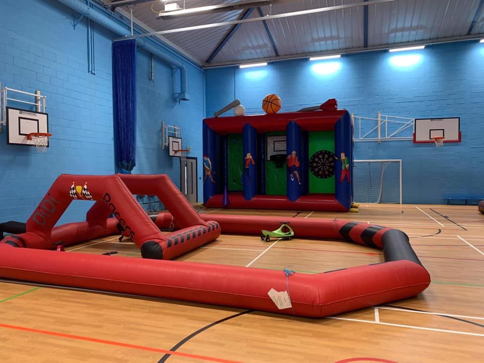 Red inflatable Didi Racers track laid out on a sports hall floor with a green Didi car, basketball hoops behind