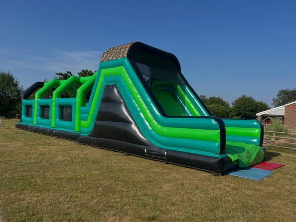 Inflatable assault course and slide set up on a grass field
