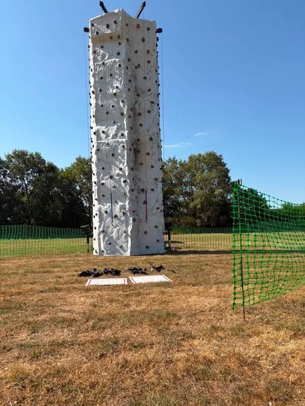 Climbing wall with landing mats and harnesses set up on grass at the Havant Festival Family Fun Day