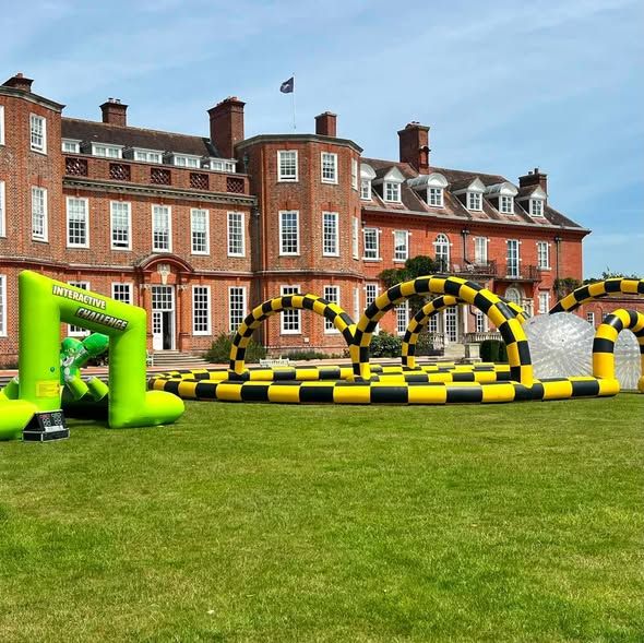 Black and yellow inflatable zorbing course with clear zorb balls on the lawn in front of Walhampton school
