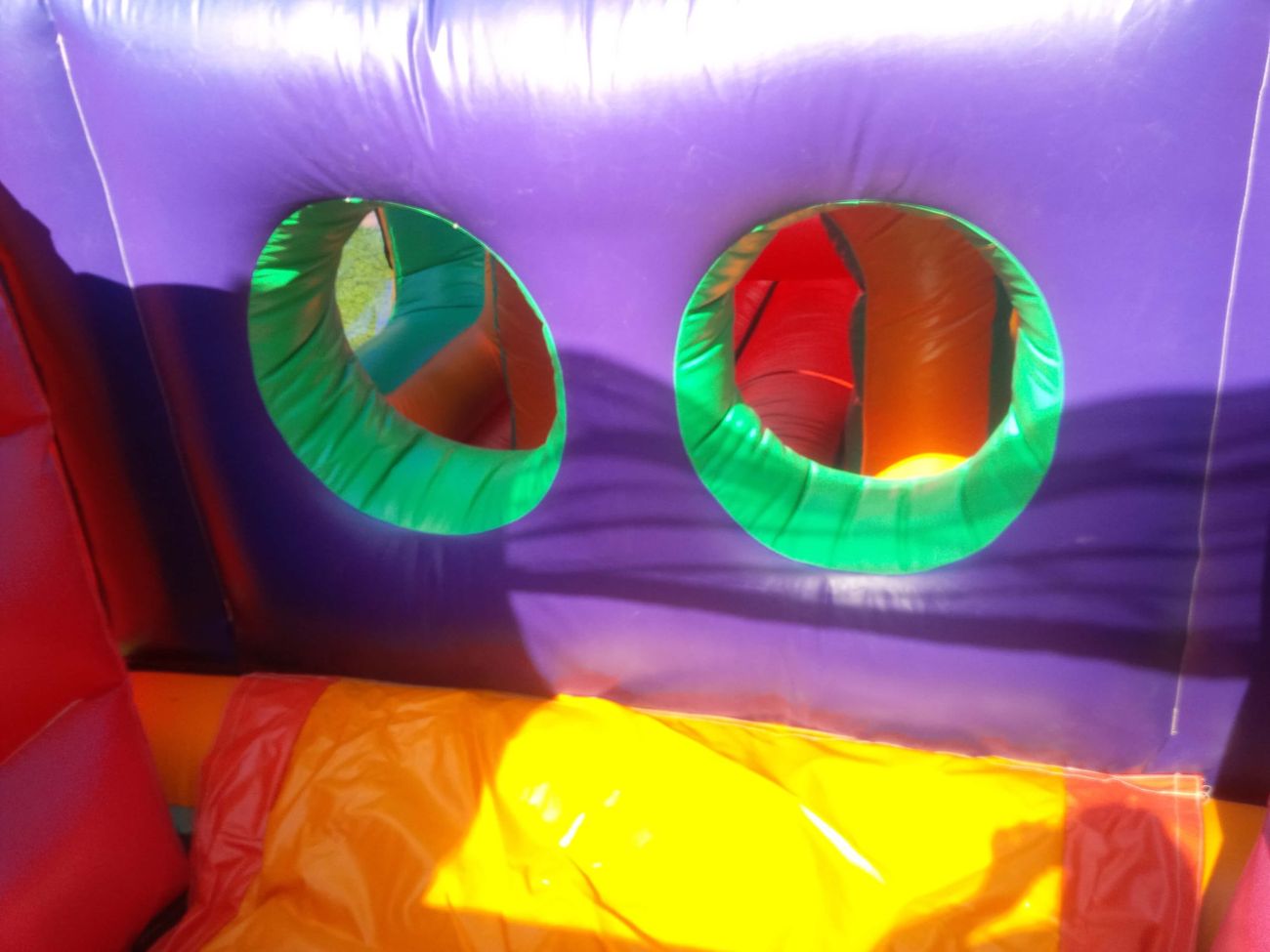 Interior with purple walls, two green-rimmed circular porthole windows and yellow floor padding