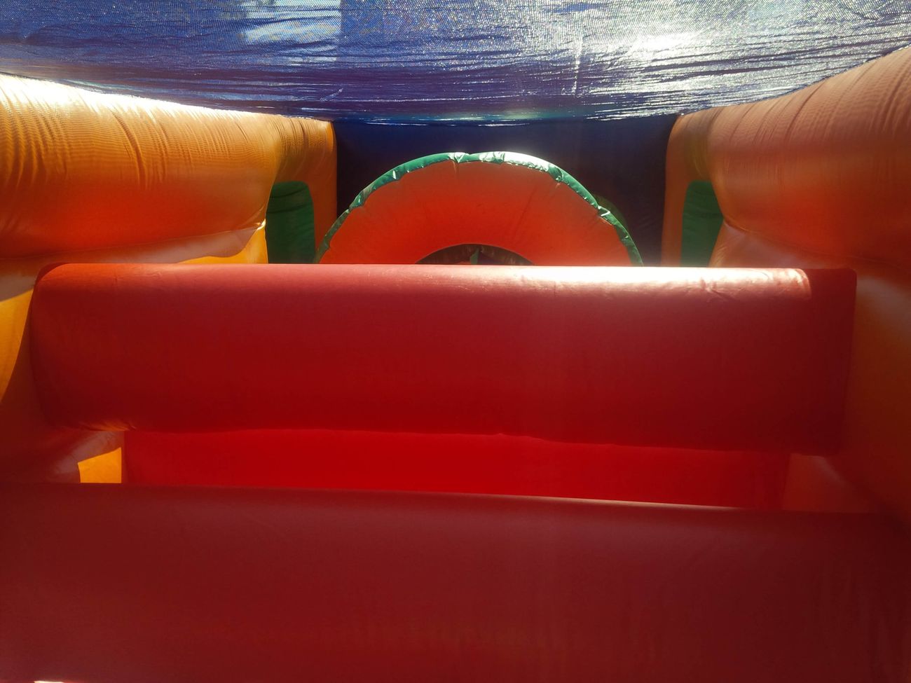 Inside the assault course looking toward red padded hurdles and an orange tunnel ahead