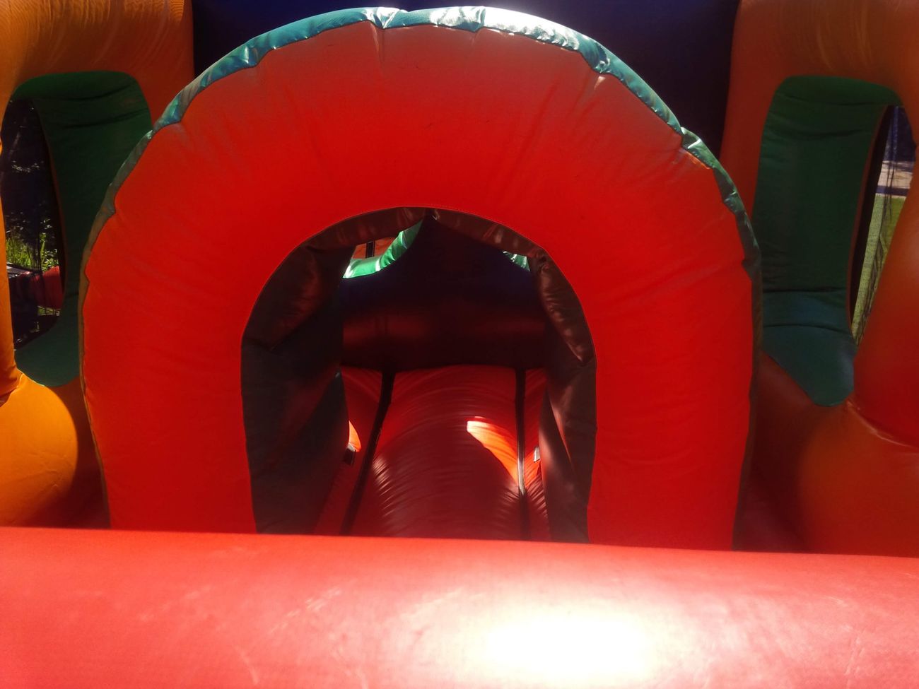 Orange tunnel entrance with green trim inside the assault course, red padded floor in foreground