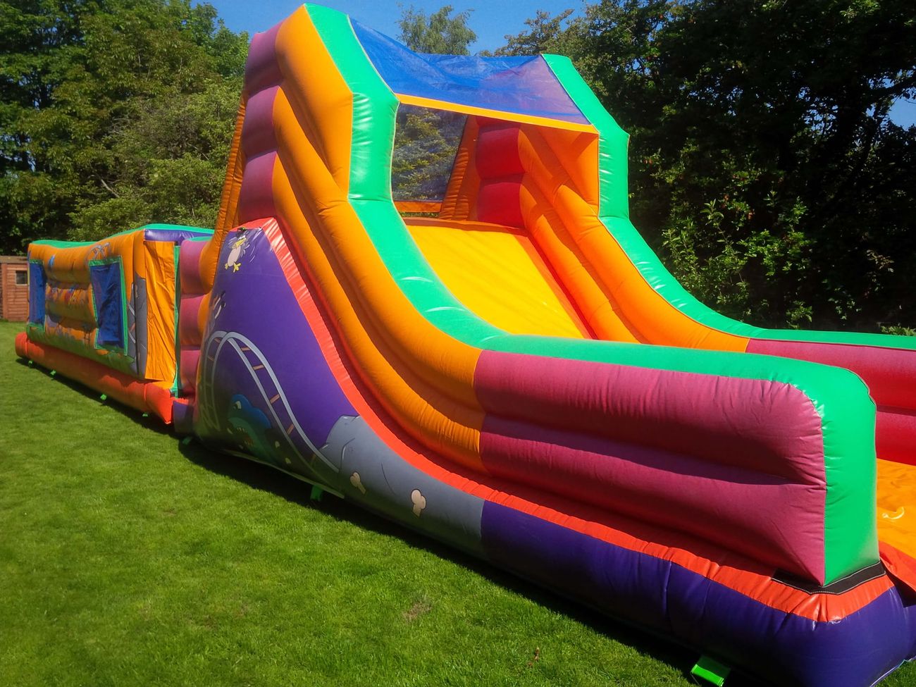 Rear view of slide showing orange bed, green and pink walls, purple lower section, set on grass
