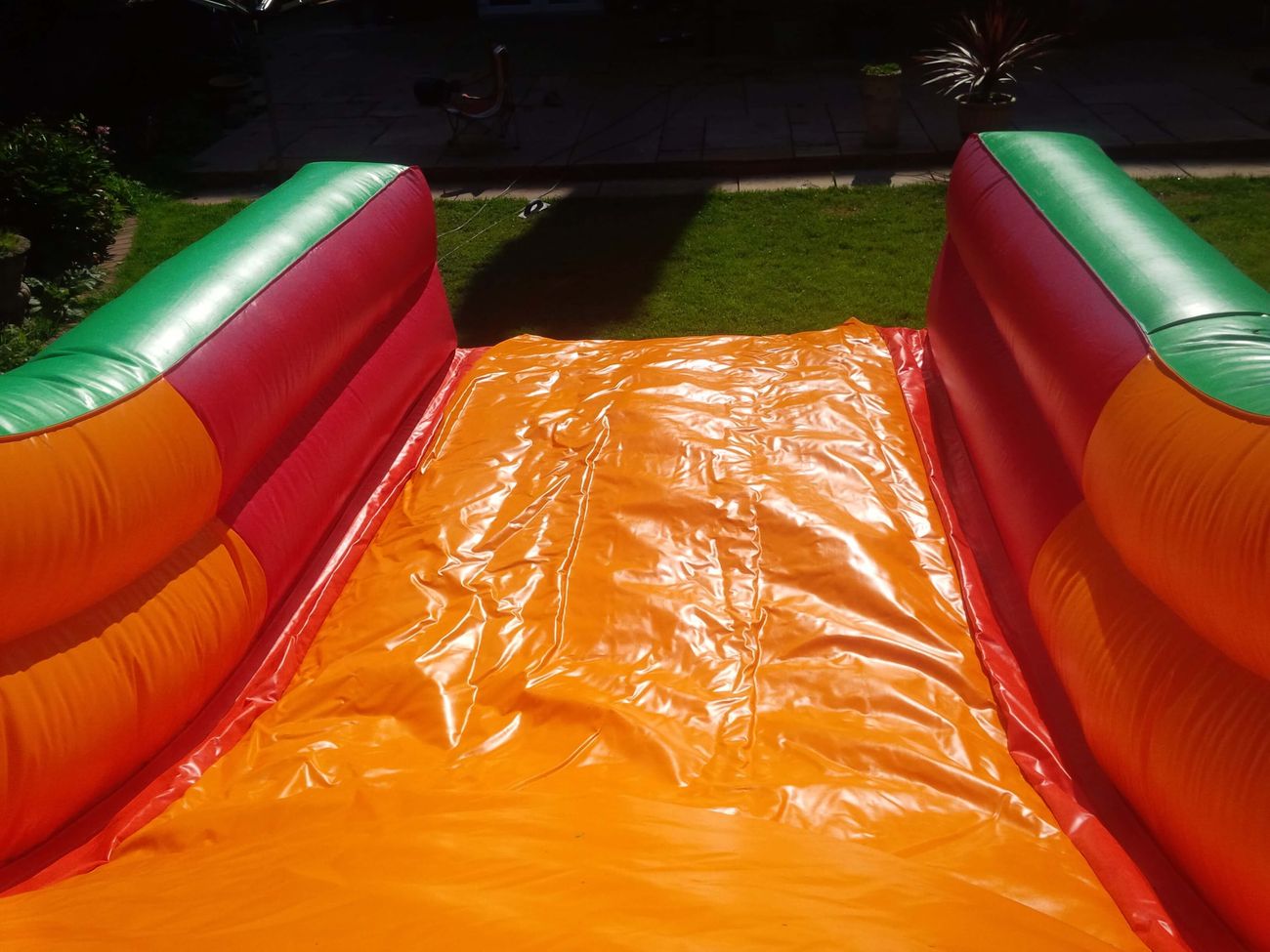 View from top of orange slide bed looking down toward grass, red borders and green-topped walls