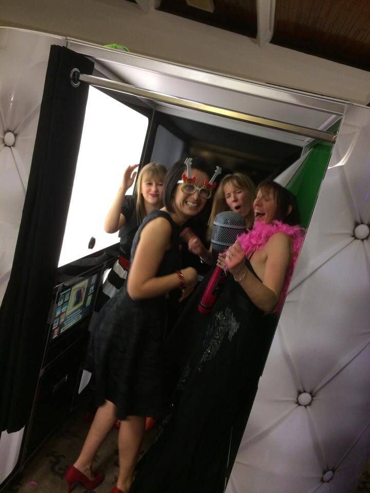 Four guests posing with props and a microphone inside the photo booth