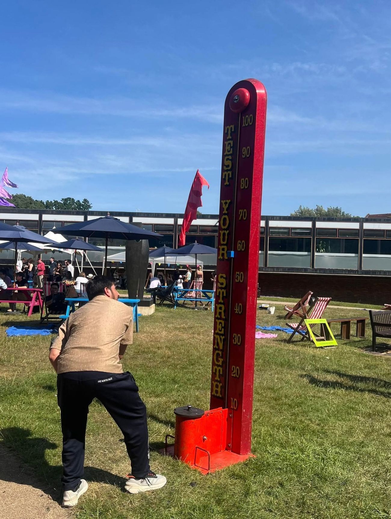 Test Your Strength high striker set up on grass at an outdoor fun day with picnic tables and bunting