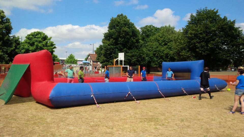 Teams strapped in and playing on the ropes pitch at a park with a basketball hoop behind