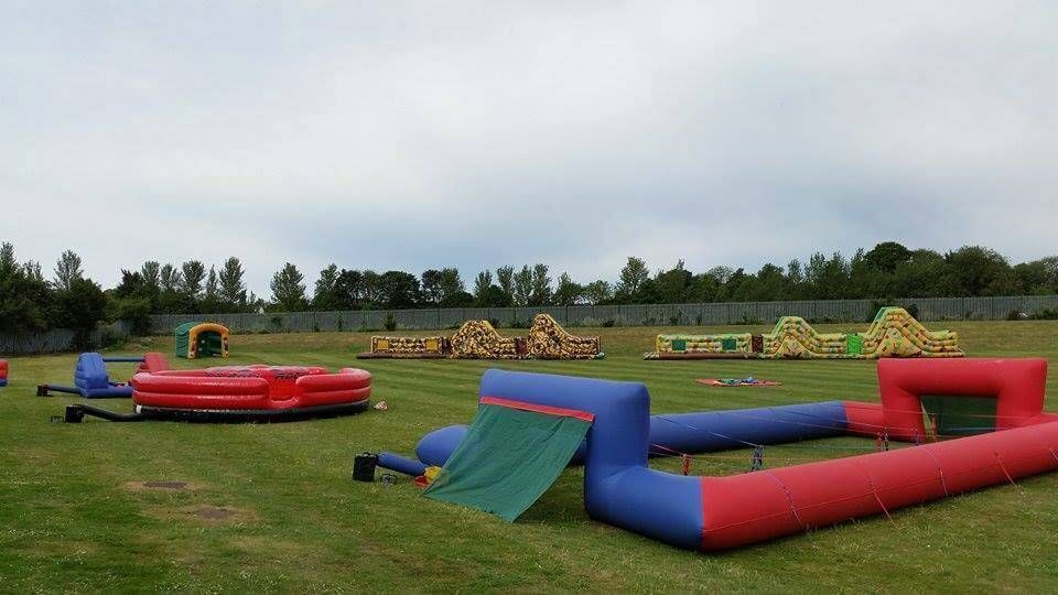 The empty ropes pitch on a grass field with inflatable assault courses behind