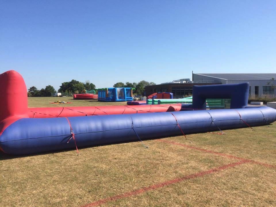 Side view of the red and blue ropes pitch on grass under a clear blue sky