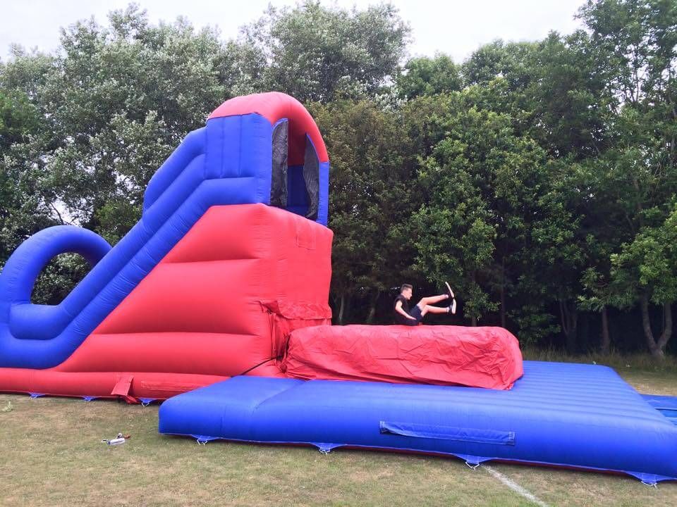 Red and blue inflatable base jump on grass, jumper in the air above the red landing bag