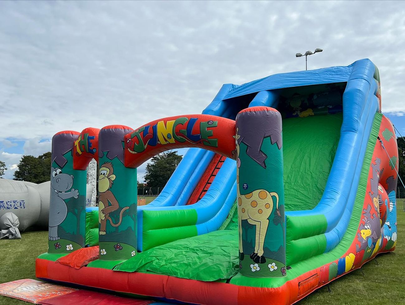 Jungle Event Slide inflatable: 'THE JUNGLE' arch with hippo, monkey and giraffe, blue slide bed
