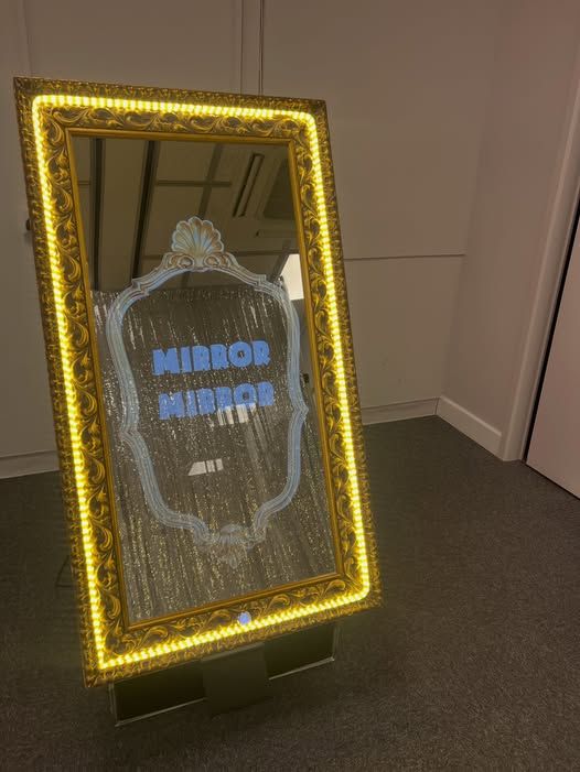 Magic Selfie Mirror showing Mirror Mirror on its screen, silver tinsel backdrop reflected opposite at Andover College