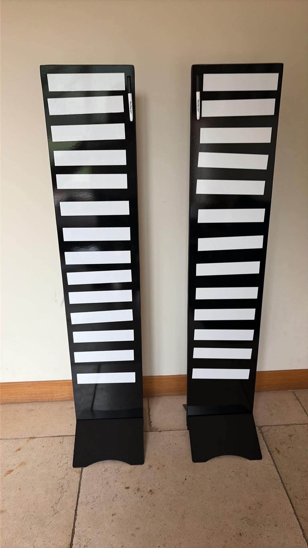 Pair of tall black magnetic leaderboard boards with ten white strips and clipped markers