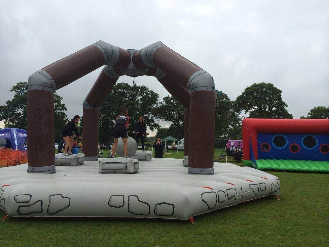 Players on the pedestals reaching for the wrecking ball under the tall brown arch