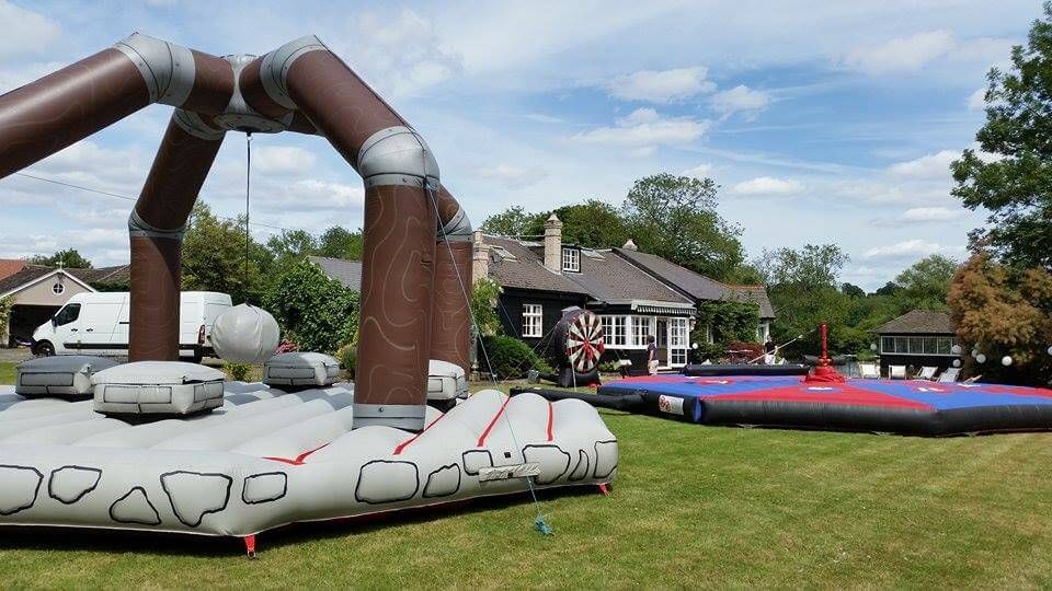 Medieval Human Demolition set up on a private venue lawn beside other inflatables