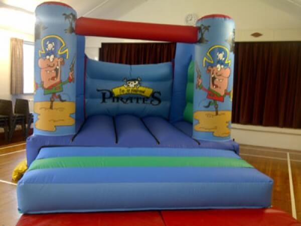 Blue pirate bouncy castle with cartoon pirates set up inside a community hall
