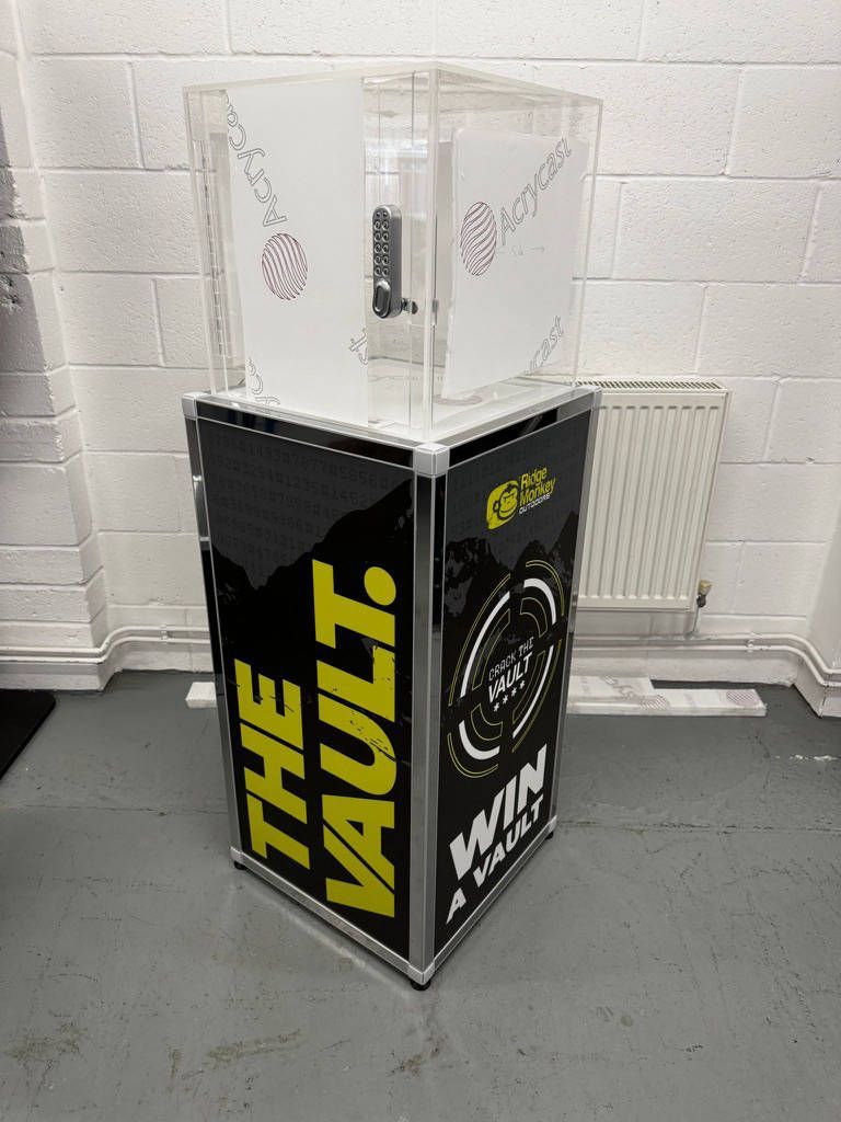 Crack the code prize vault: clear acrylic case with combination lock on a black branded plinth