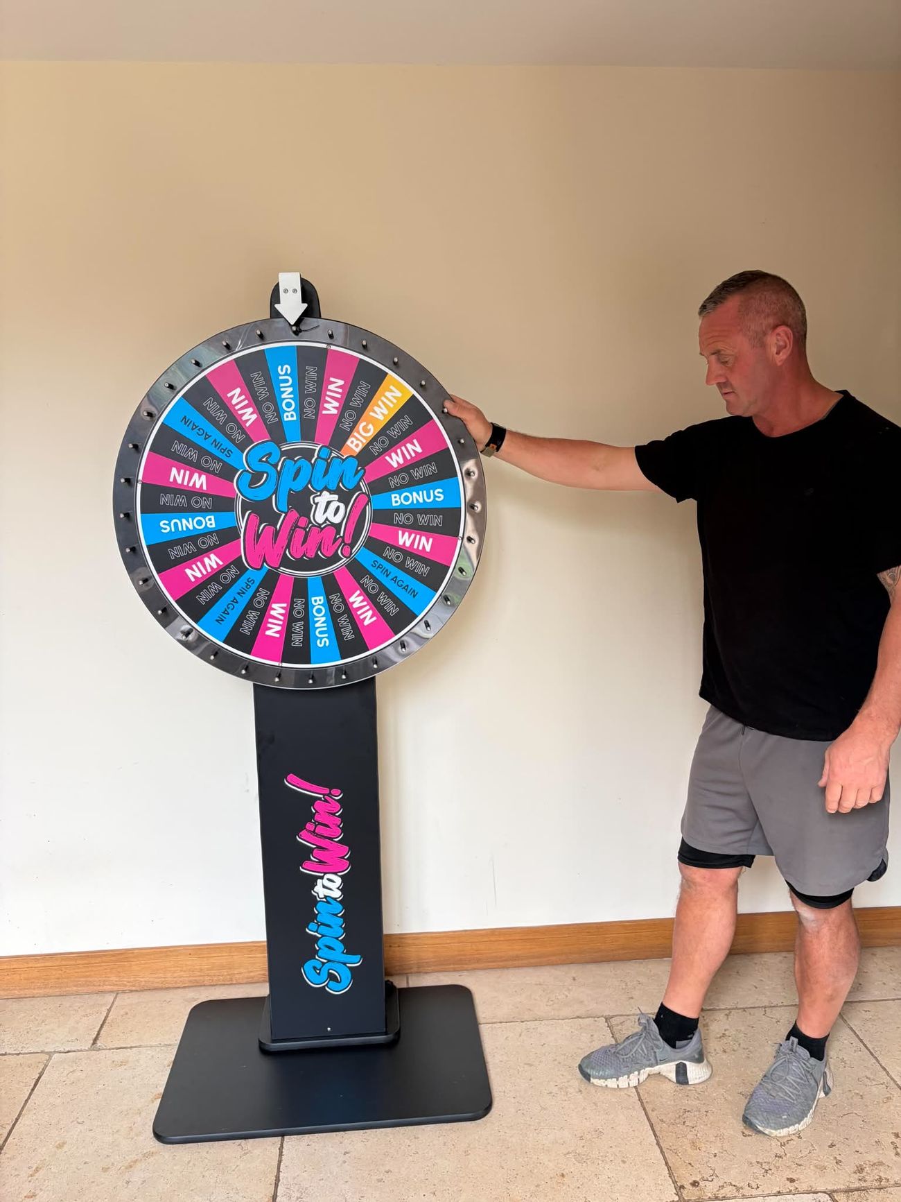 Team member beside the Spin to Win prize wheel to show its height