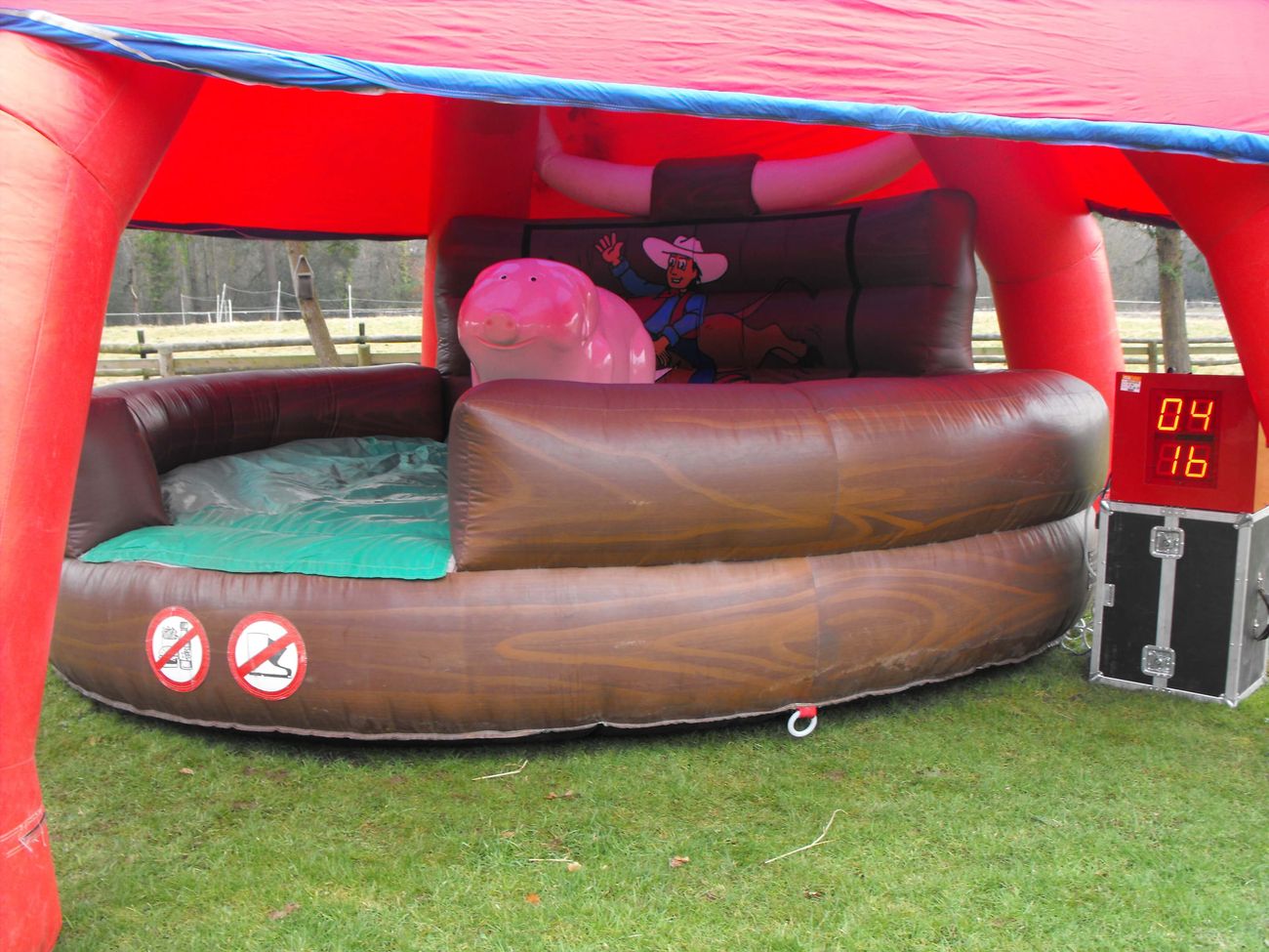 Rodeo pig under the red spider marquee on grass, brown inflatable surround and LED timer alongside