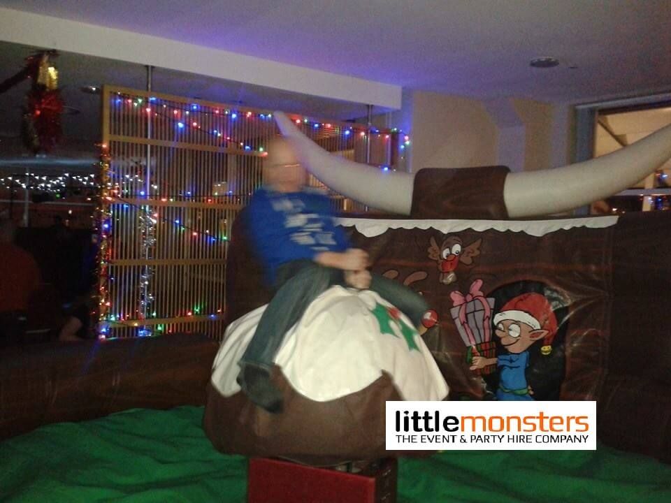Rider on the Christmas pudding rodeo at a party with fairy lights and Christmas decorations behind