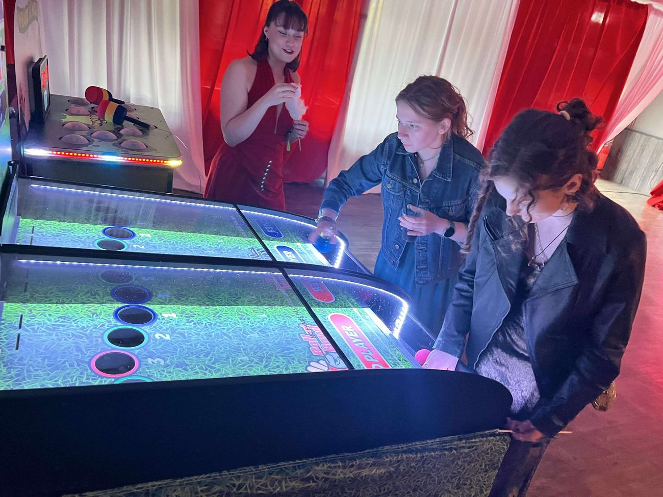 Players rolling balls on the Grand National tabletop racing derby game at an indoor event