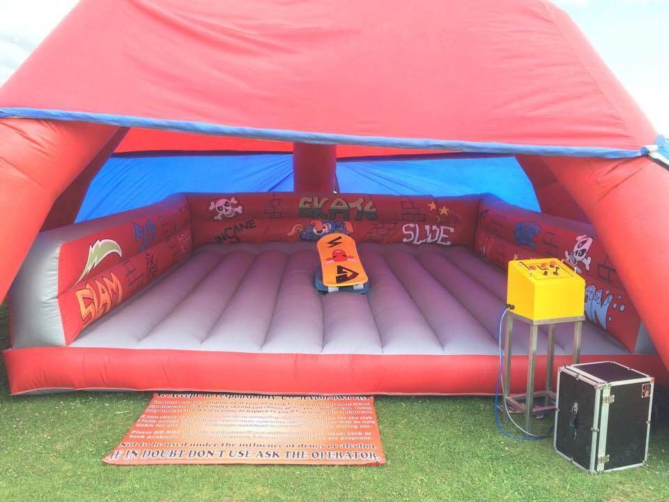 Outdoor skateboard simulator in red inflatable enclosure with control box on grass