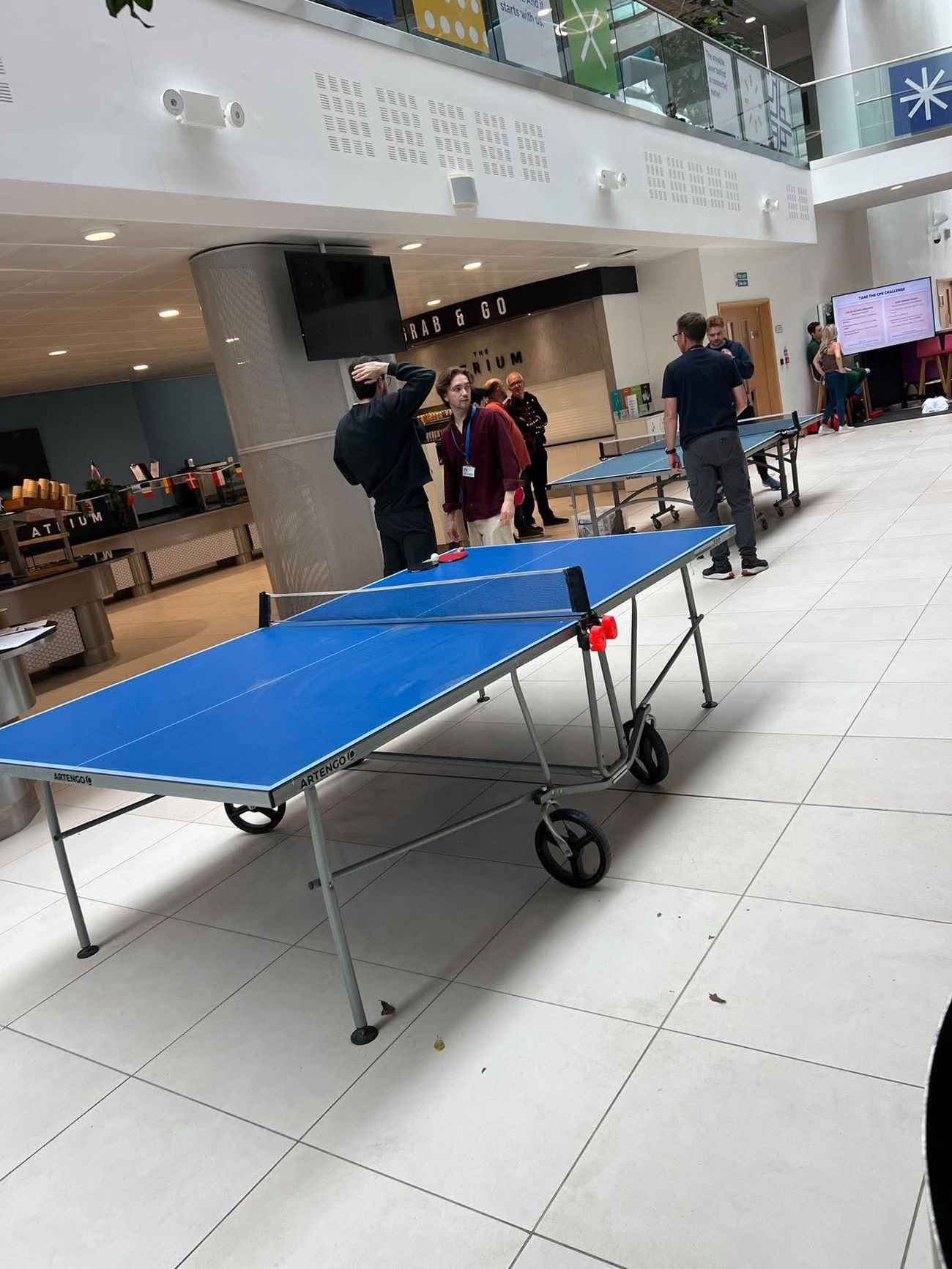 Side view of a blue table tennis table during a corporate atrium game