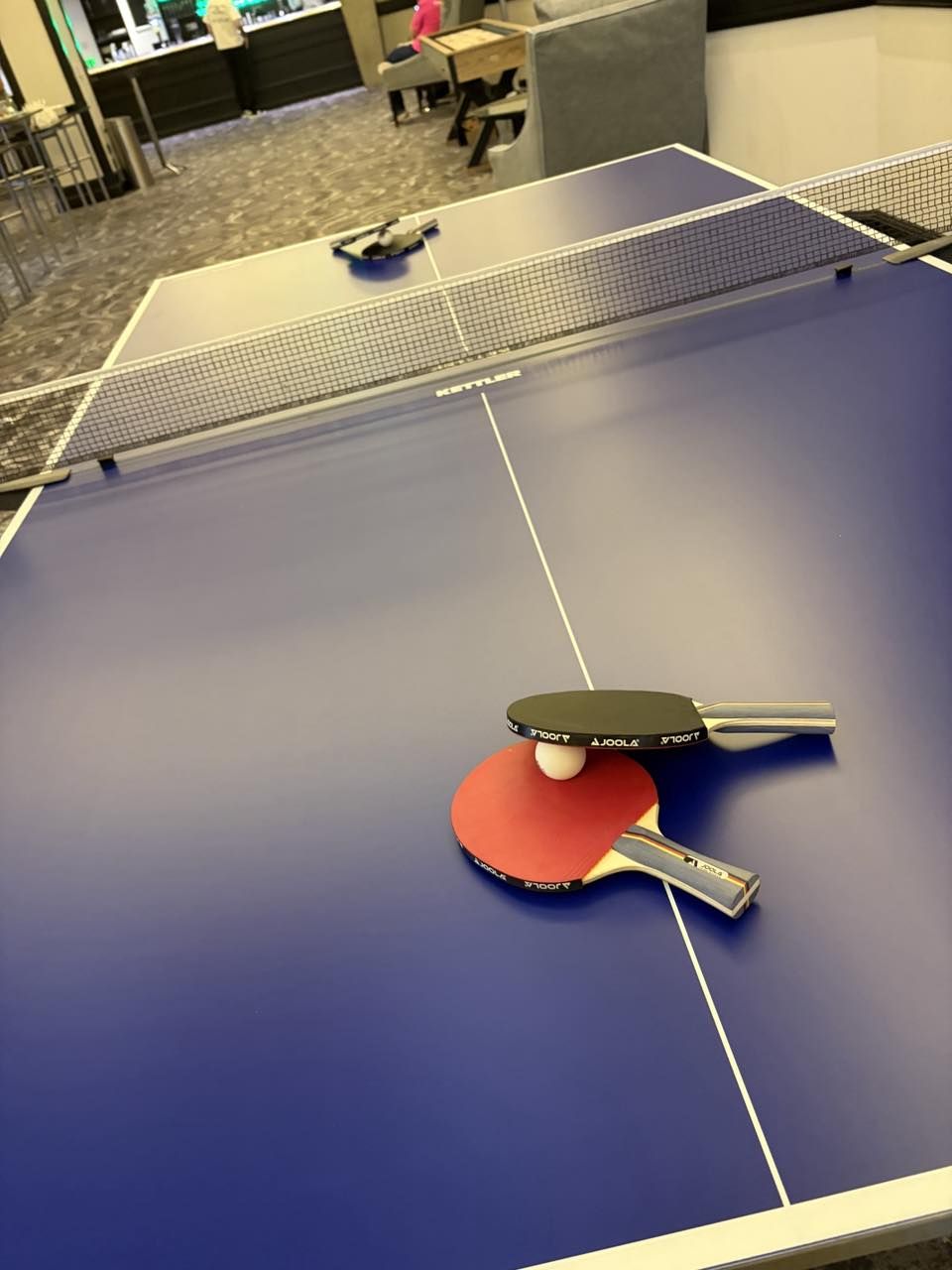 JOOLA bats and a ball resting on the blue table tennis table