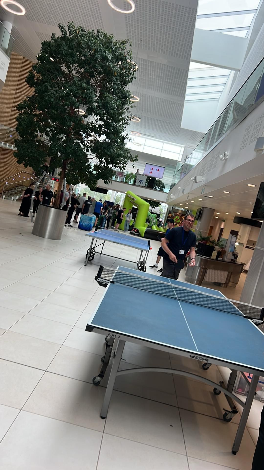 Blue table tennis table in an indoor event space with other games behind it