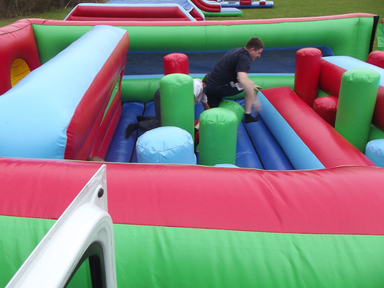 Player climbing over the padded pillars and barriers inside the Challenger course