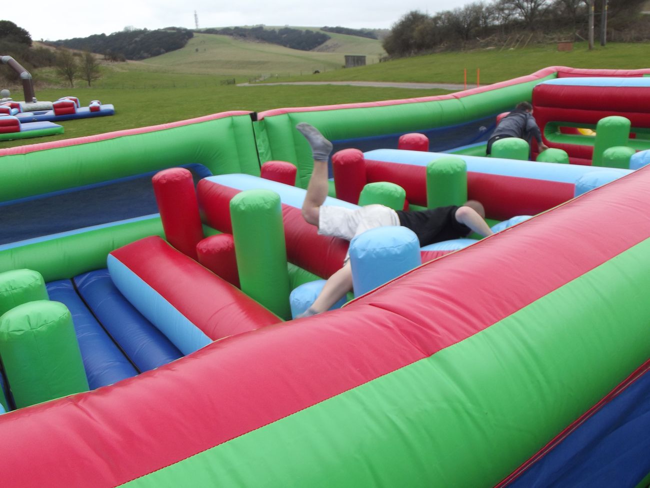 Player tumbling over an inflatable barrier inside the Challenger course on a field