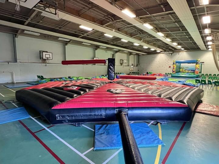 Sweeper set up indoors in a sports hall, numbered podiums around the central padded arms, crash mats at the edges