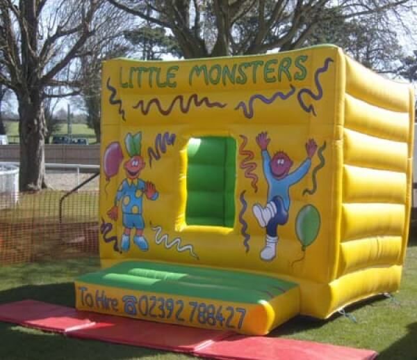 Yellow Tweenies box bouncy castle with a window entrance and Tweenies characters, on grass