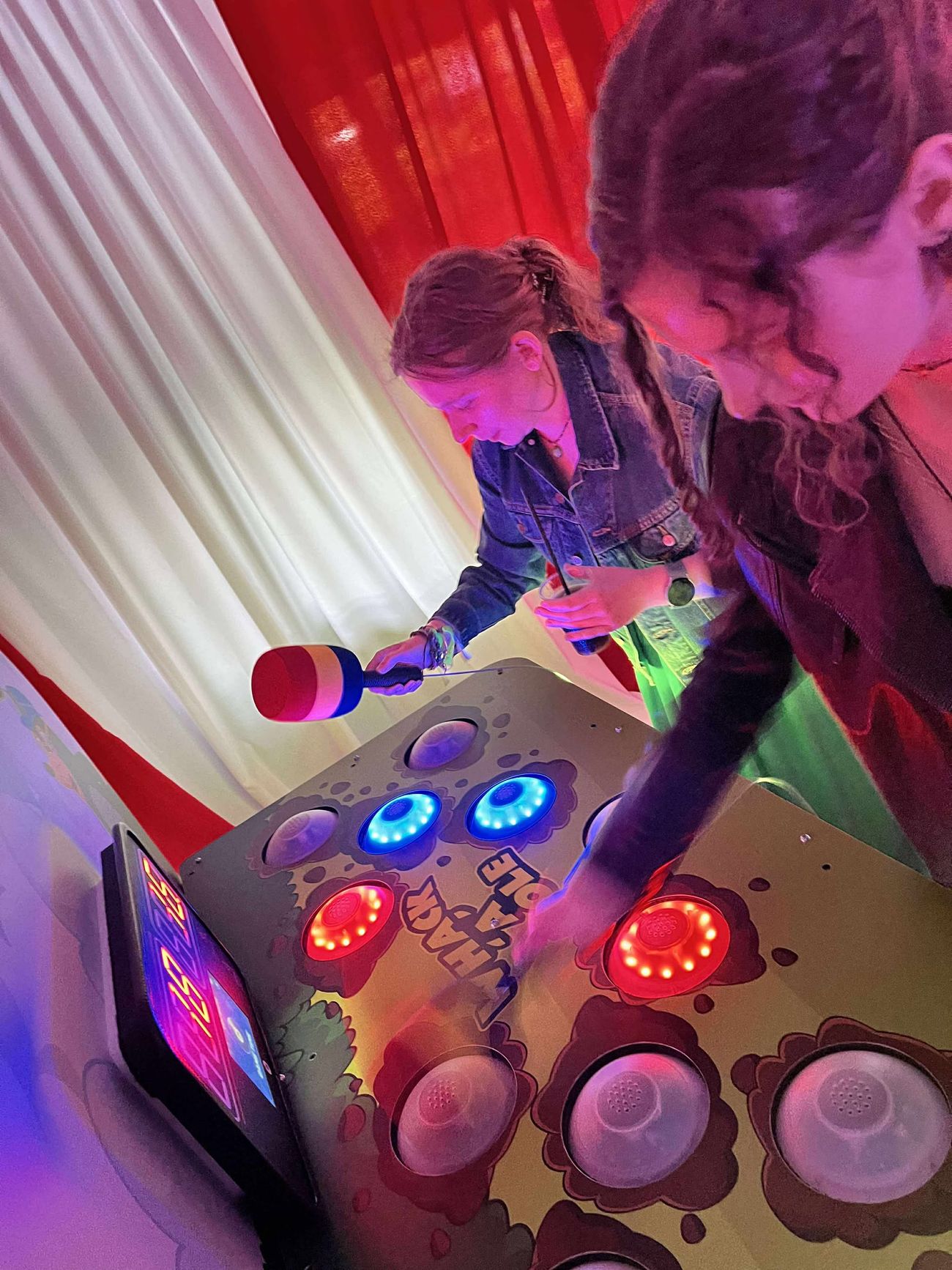 Foam hammer hitting a red lit target on the Whack A Mole game