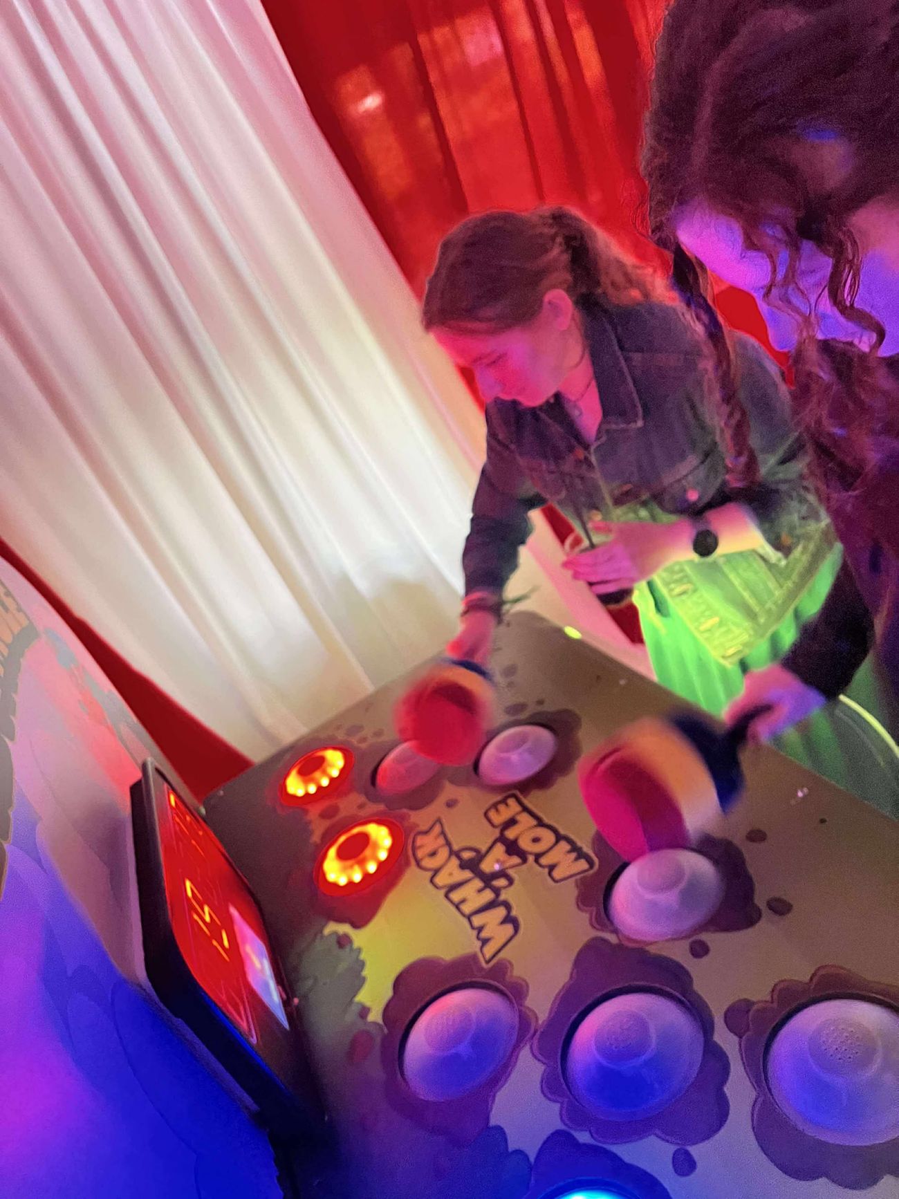 Whack A Mole player reaching across the cabinet to hit a glowing target