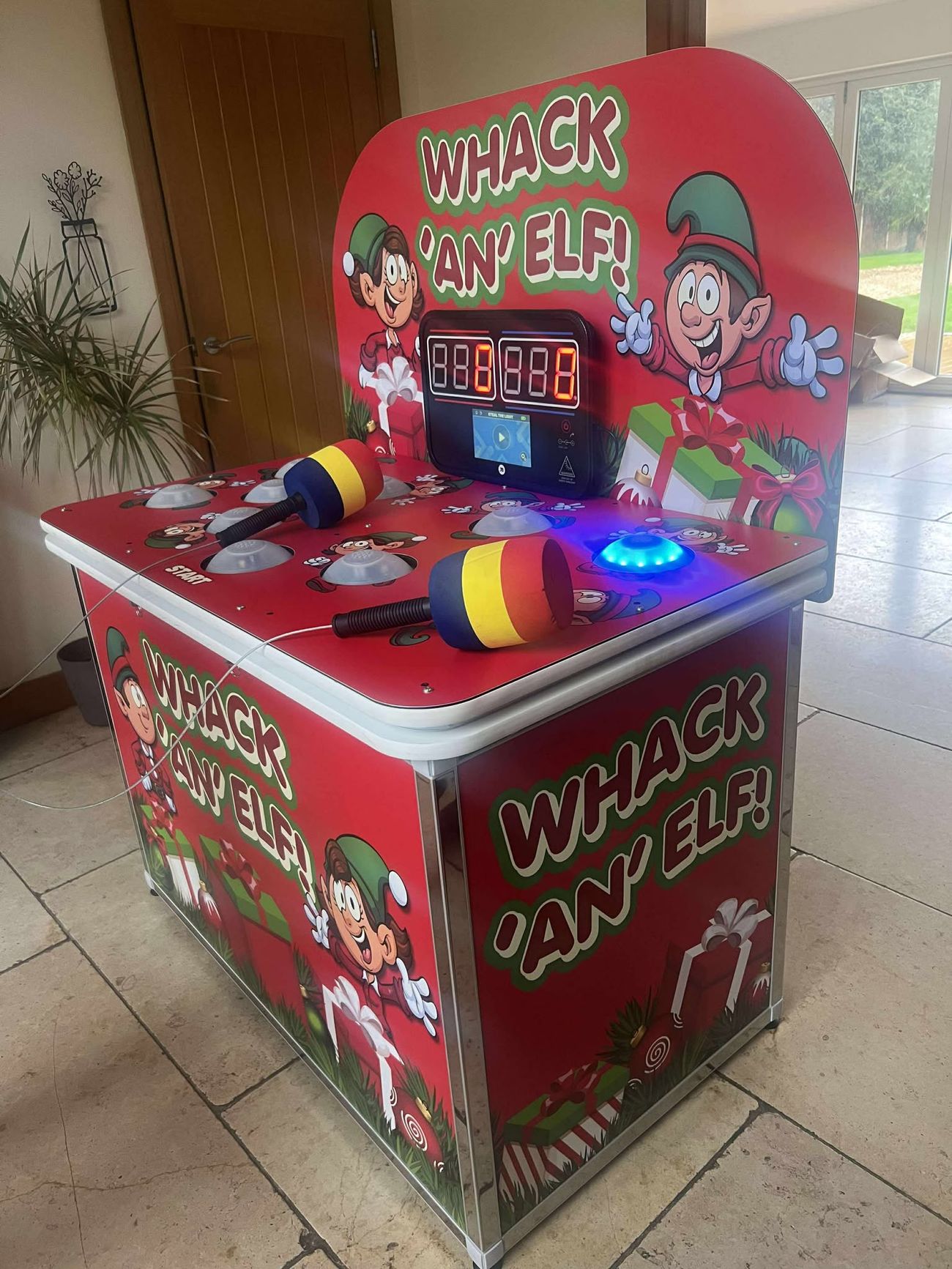 Angled view of the red Whack an Elf game with one dome glowing blue and the scoreboard behind